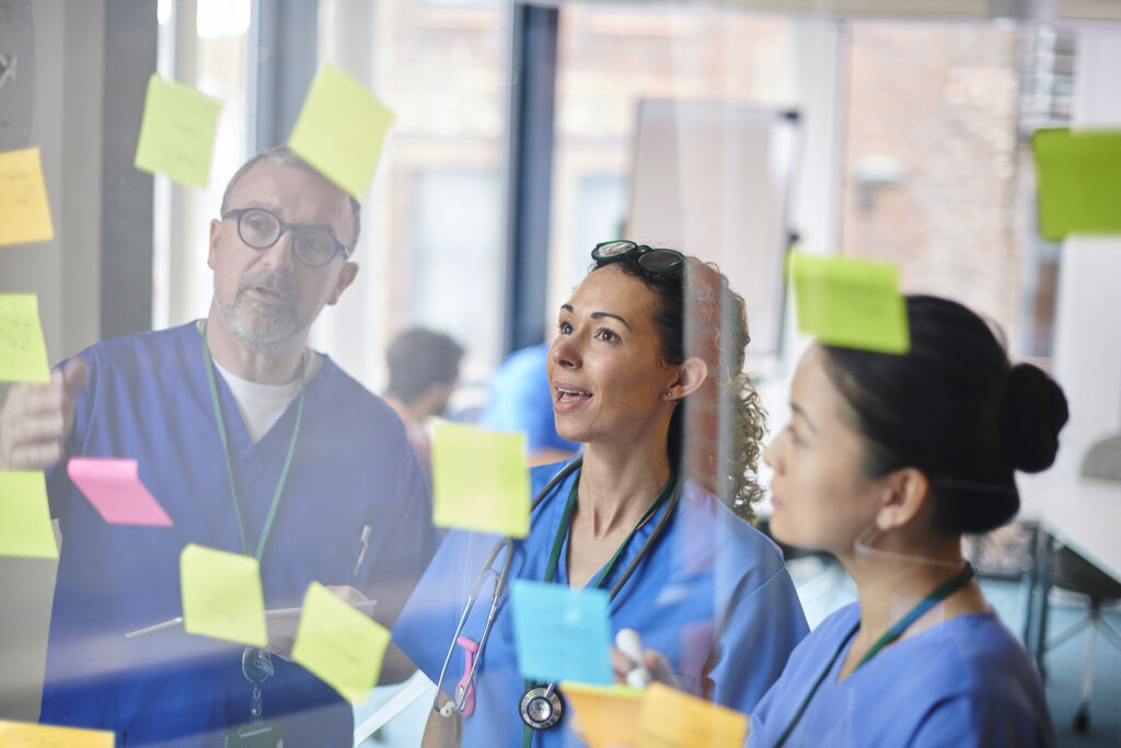Medical team reviews post-its on a board
