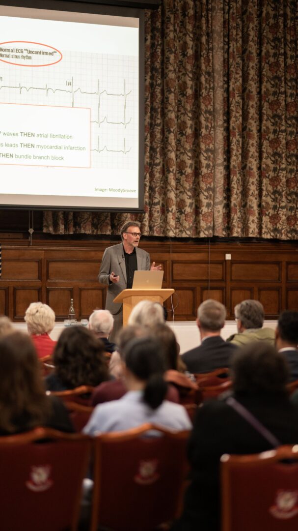Niels Peek, Professor of Data Science and Healthcare Improvement, giving a lecture in front of a wooden podium at THIS Institute and Homerton College's annual lecture.