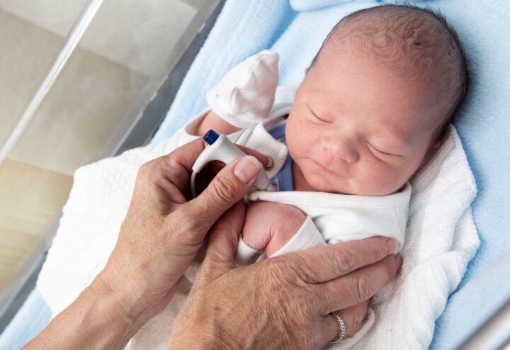 Picture of newborn baby and two hands cradling them